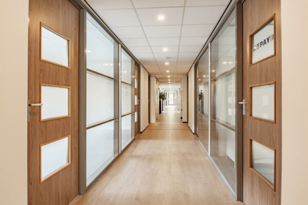 Licht en modern kantoorinterieur met houten deuren en glazen wanden aan de Burgemeester Verderlaan.